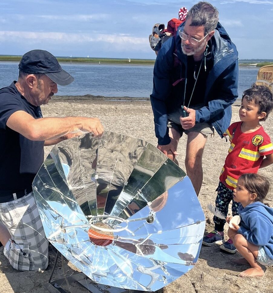 Sur cette photo, adultes comme enfants semblent stupéfaits devant l'ingéniosité de la parabole du barbecue solaire SUNplicity.